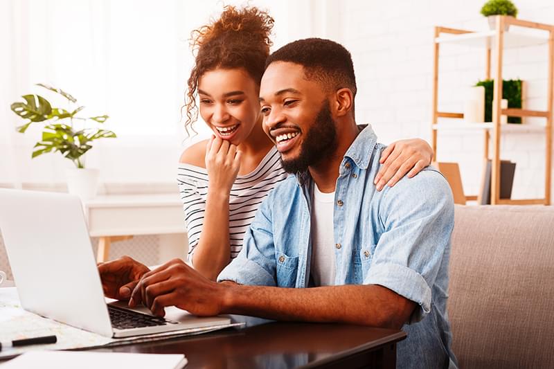 Smiling woman taking notes in front of laptop